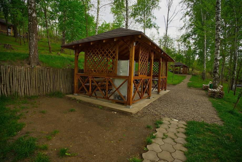 Wooden glamping cabin in forest setting with latticed porch and stone pathway