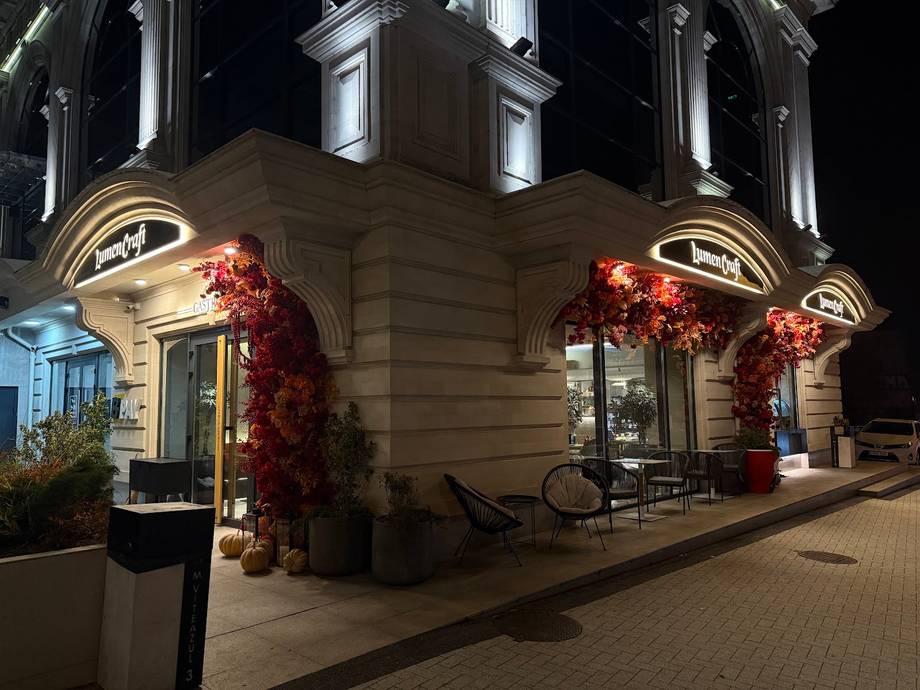 Evening exterior view of elegant stone storefront with arched entry and autumn floral decorations
