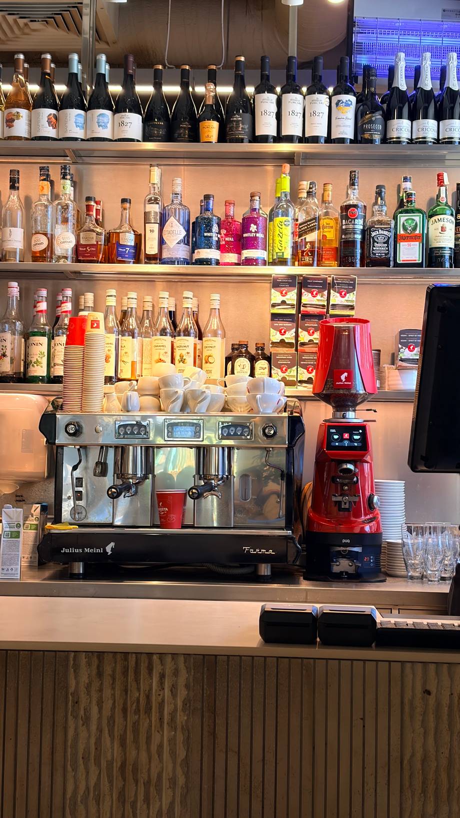 Professional espresso bar with extensive wine and spirits collection on backlit shelves