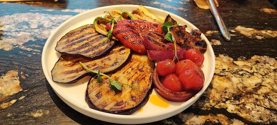 Grilled eggplant and tomato medley on white plate with herbs