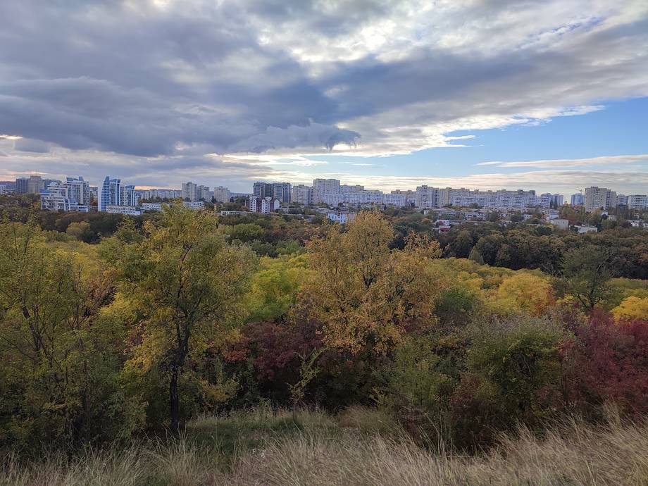Panoramic view of Chisinau cityscape from a green hillside, autumn season