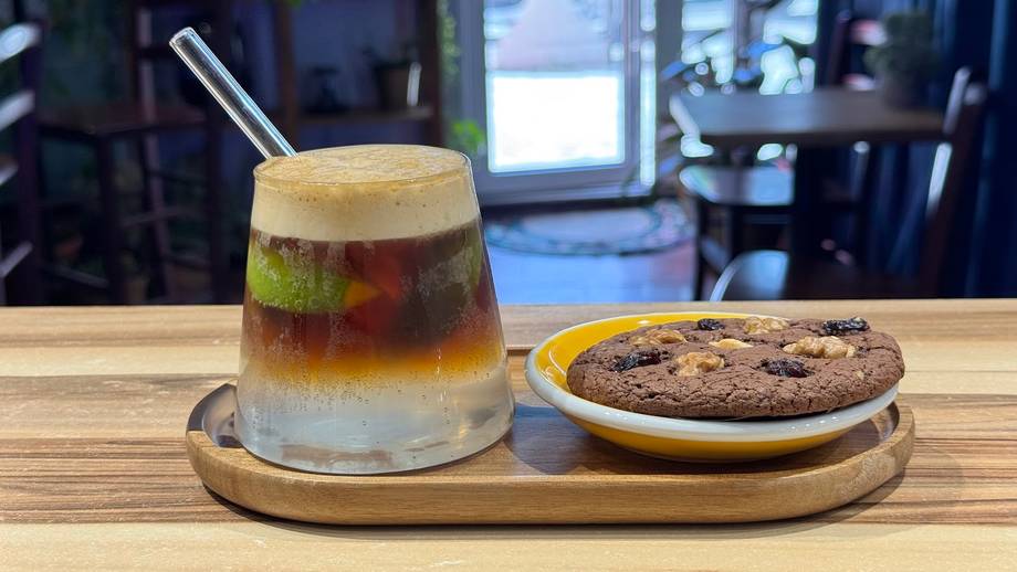 Iced beverage with green layer and chocolate cookie on wooden serving board