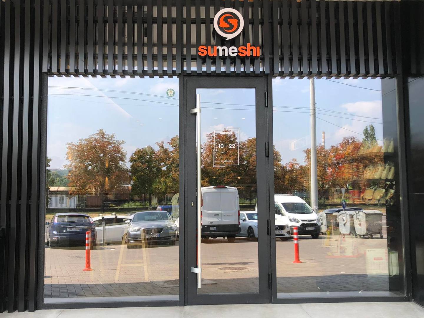 Storefront exterior with Sushi logo and parking lot view