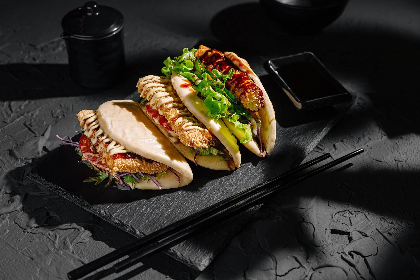 Plated gourmet sandwiches with greens and sauce on slate board
