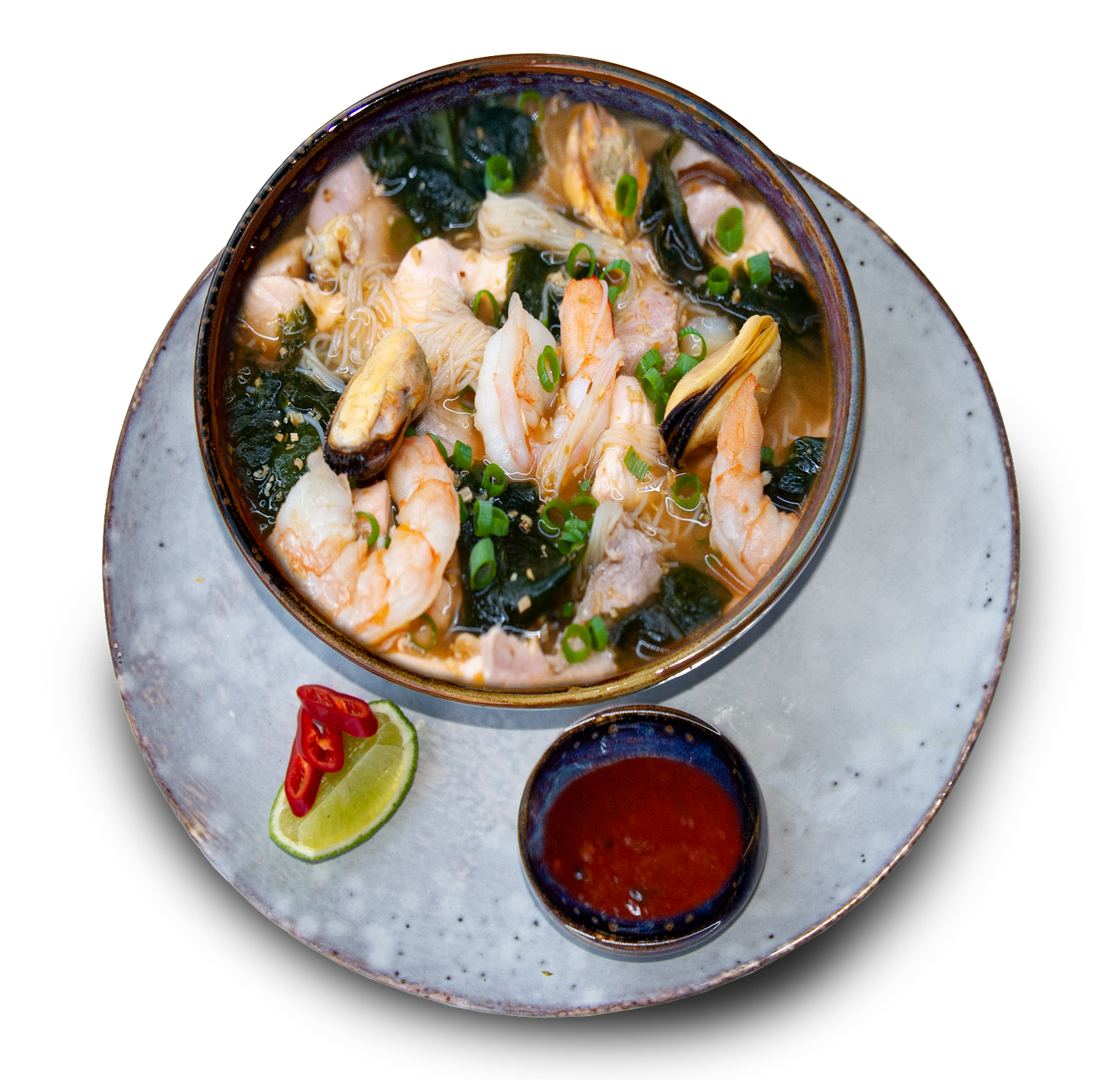 Shrimp and greens soup in ceramic bowl with lime and dipping sauce