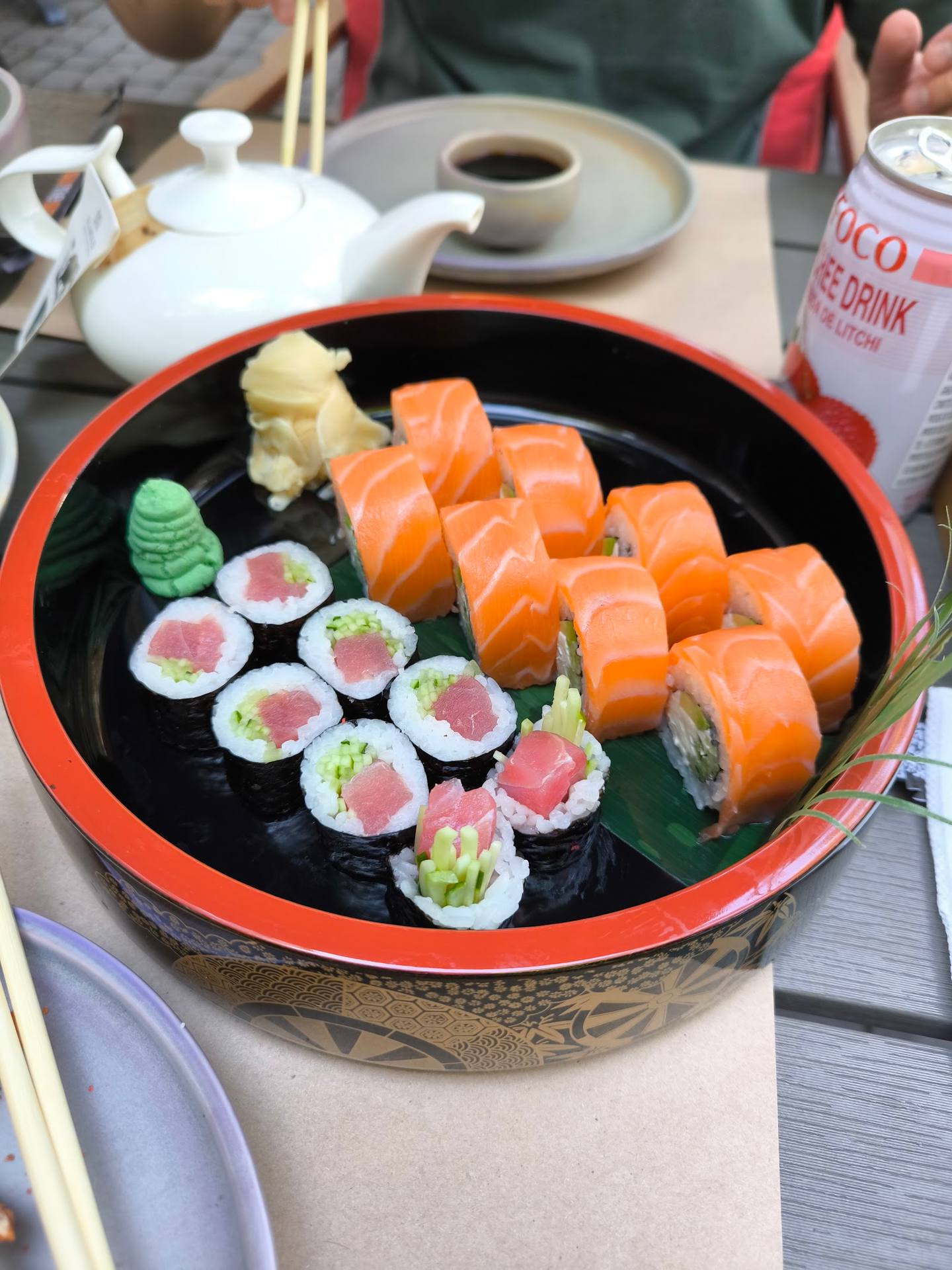 Assorted sushi platter with salmon nigiri and tuna rolls on decorative black and red dish