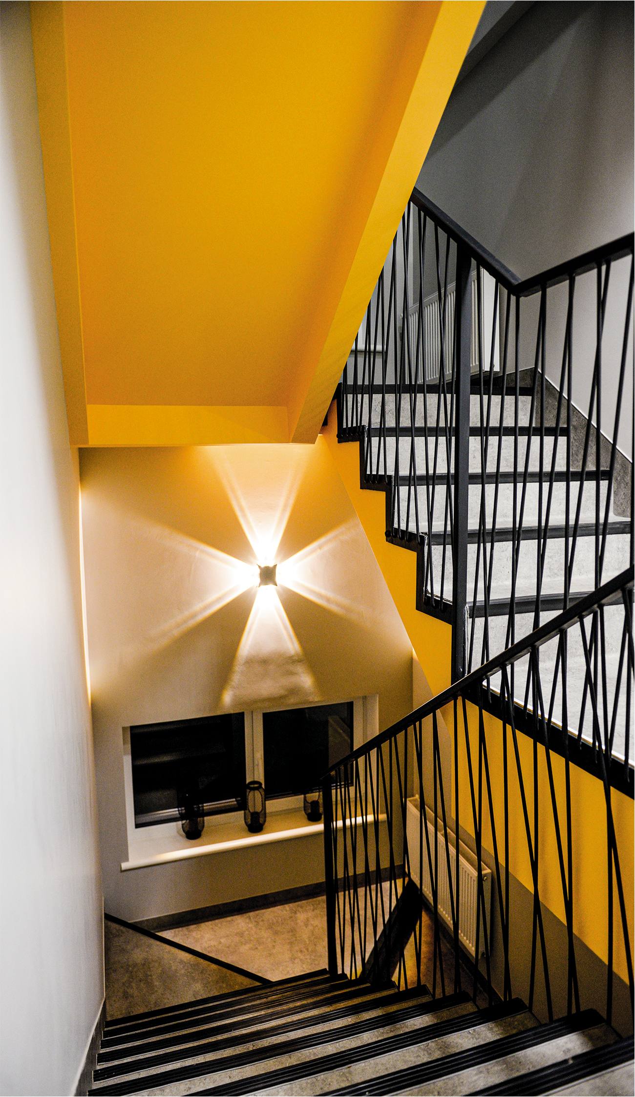 Modern stairwell with bold yellow architectural elements and black metal railing