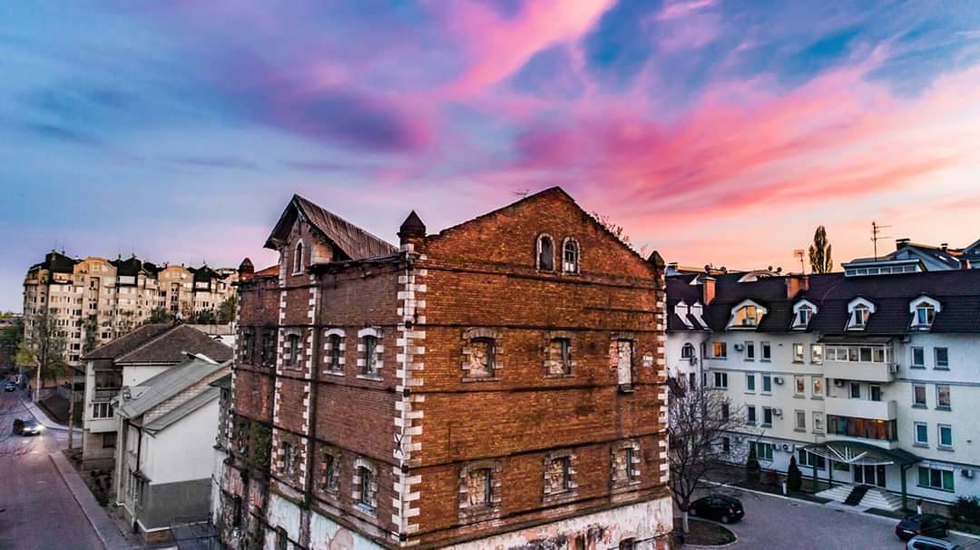 Historic brick building with distinctive architecture amid urban residential area at golden hour