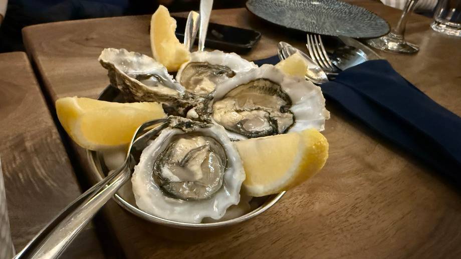 Fresh oysters on ice with lemon wedges served on wooden table
