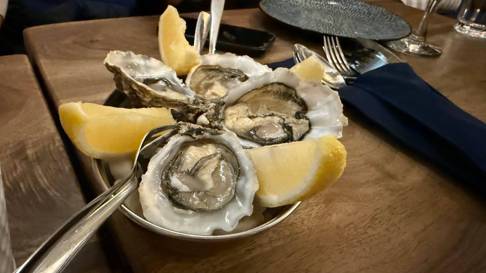 Fresh oysters on ice with lemon wedges served on wooden table