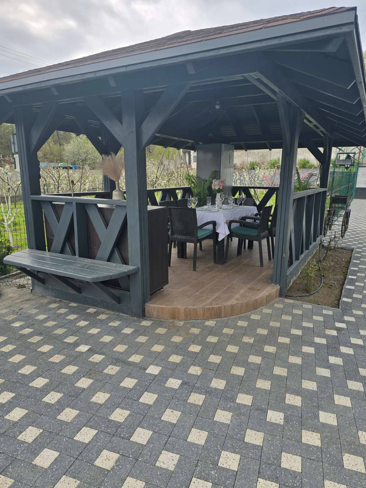 Modern wooden pavilion terrace with dining setup and patterned paving