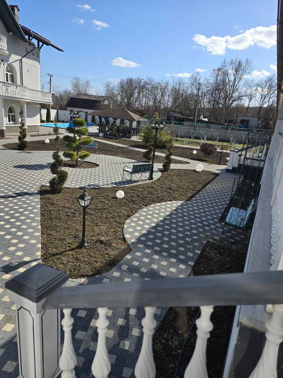 Outdoor terrace with paved courtyard, topiary landscaping, and black fence overlooking grounds