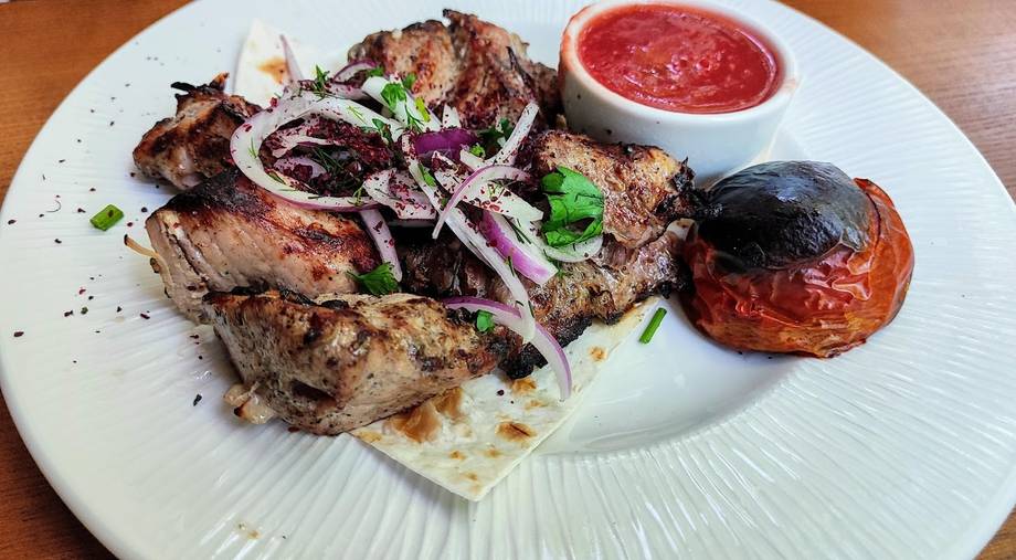 Grilled meat platter with onion slaw, sauce, and roasted vegetables