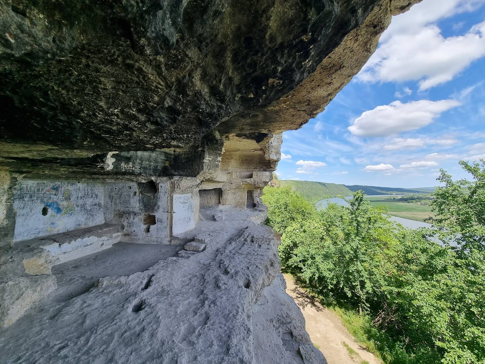 Historic cave monastery carved into cliff face overlooking verdant valley