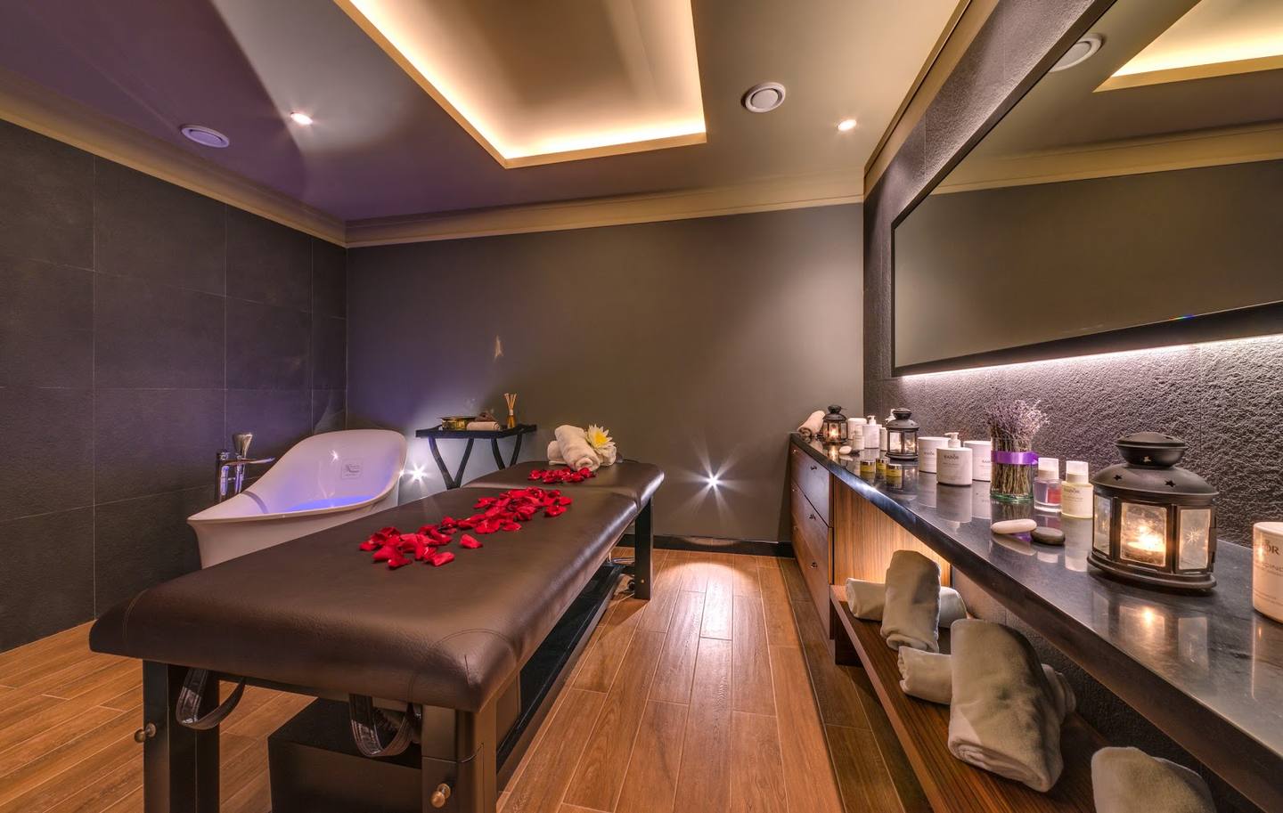 Spa treatment room with massage bed, ambient lighting, and product displays
