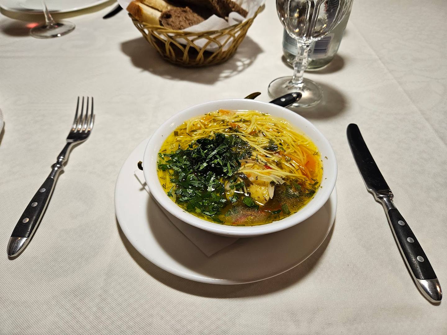 Elegant plated soup course with herb garnish and table setting
