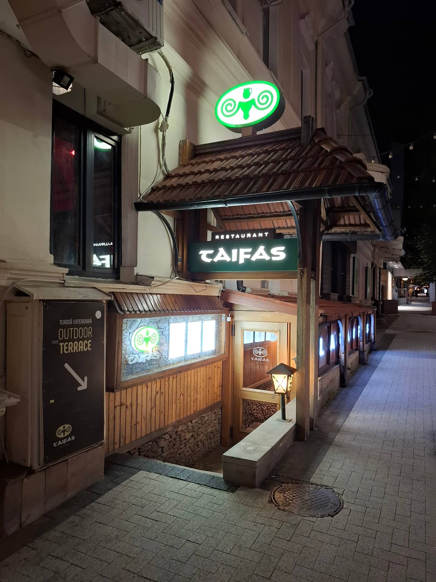 Restaurant Caifas storefront with illuminated signage at night