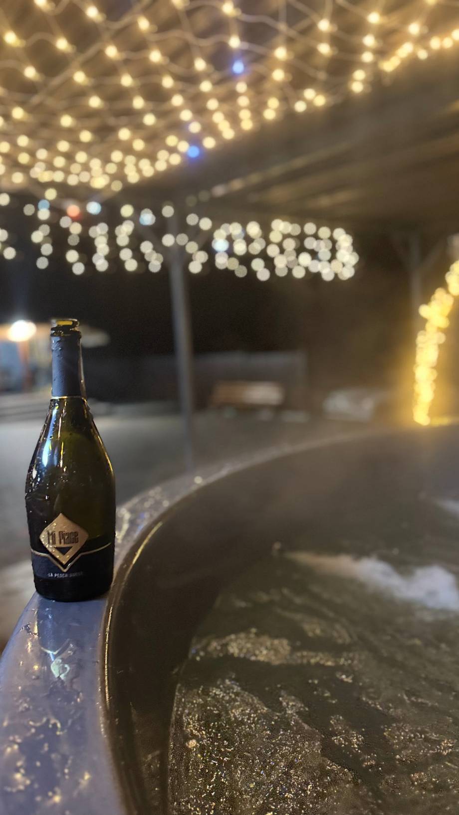 Wine bottle staged on terrace edge with string lights overhead