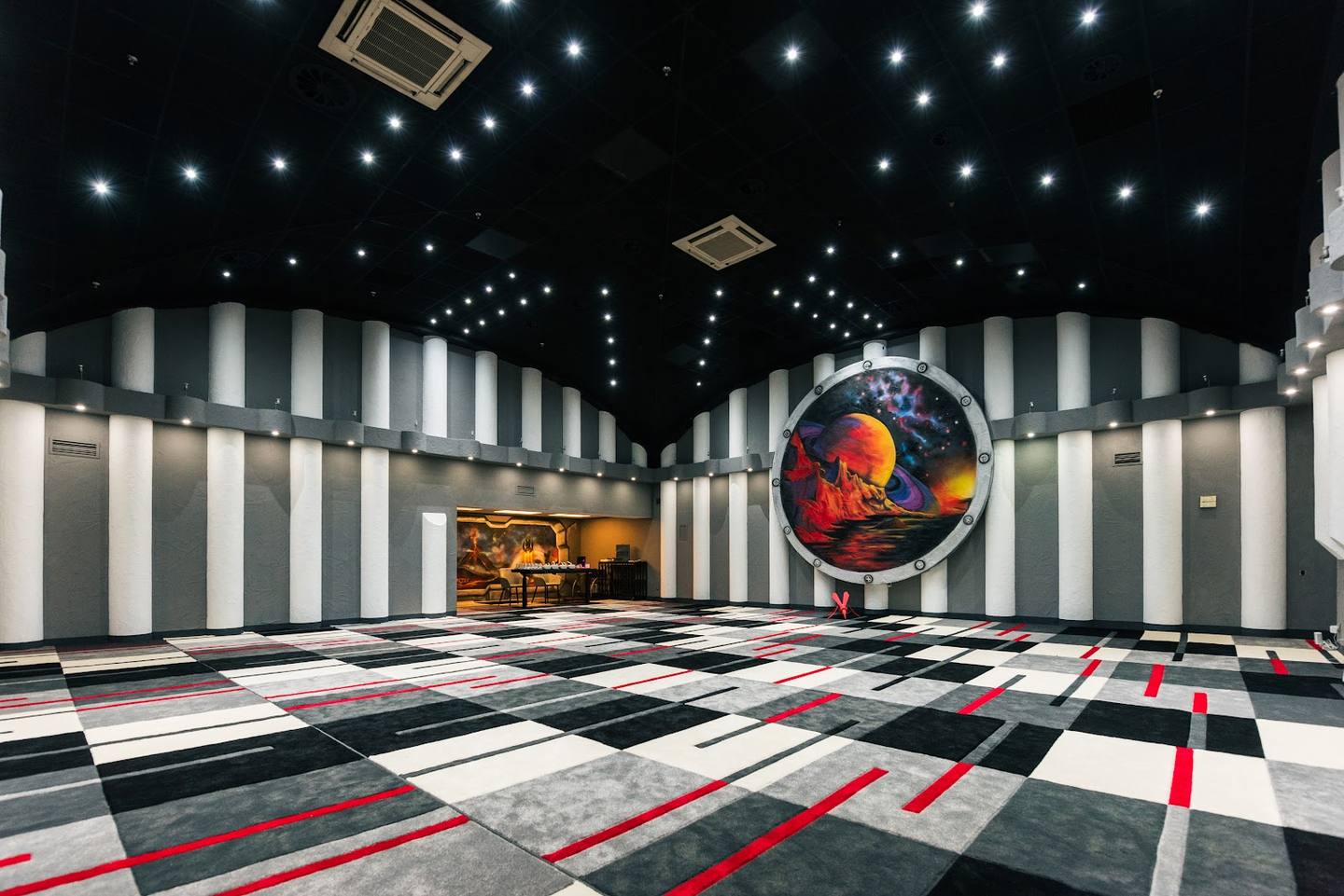 Modern nightclub interior with geometric black-and-white walls, LED ceiling lights, and colorful floor design