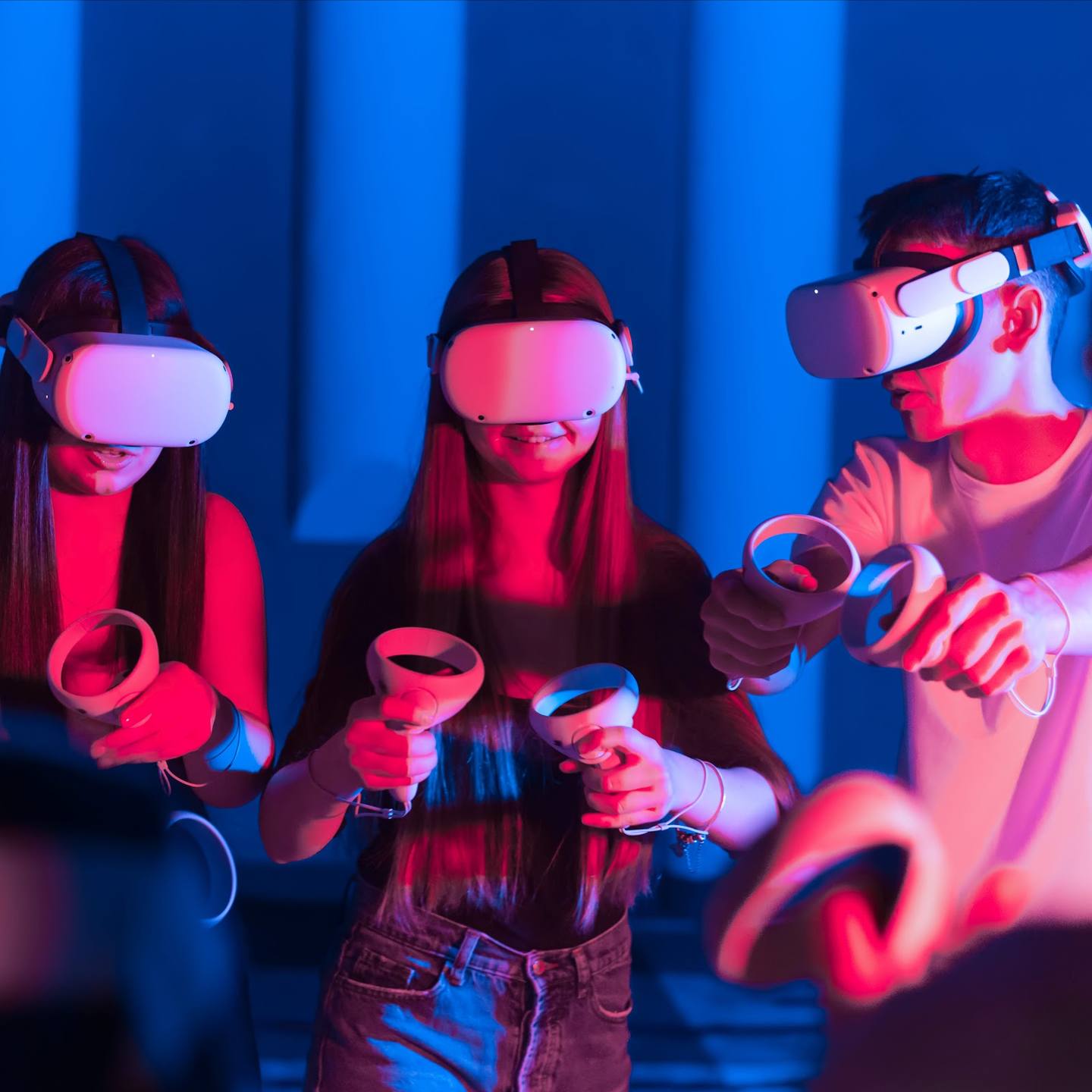 Visitors enjoying VR gaming with motion controllers in neon-lit immersive environment