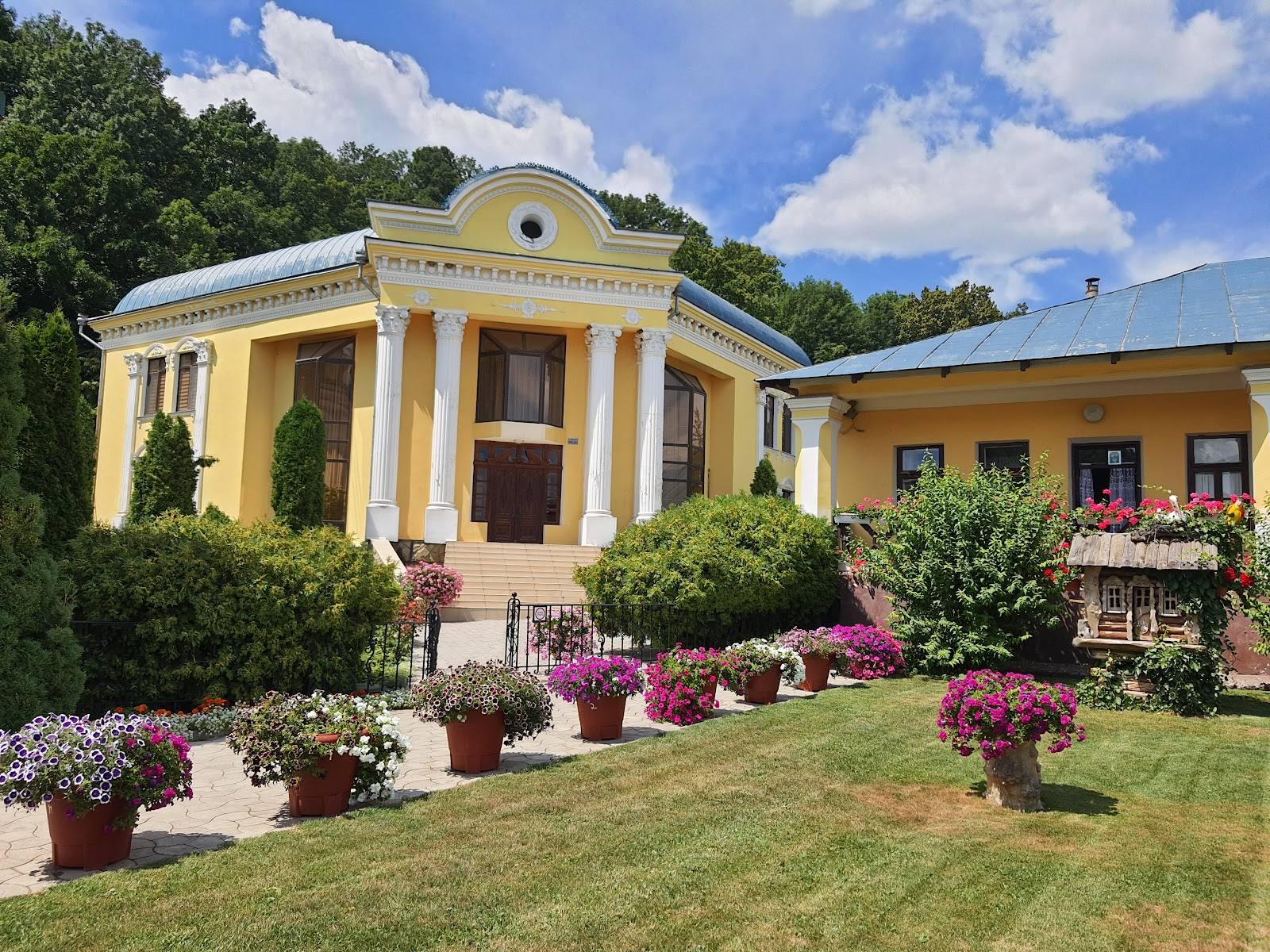 Yellow neoclassical building exterior with manicured gardens and flowering landscaping