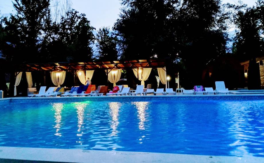 Poolside terrace at dusk with lounge seating and illuminated umbrellas