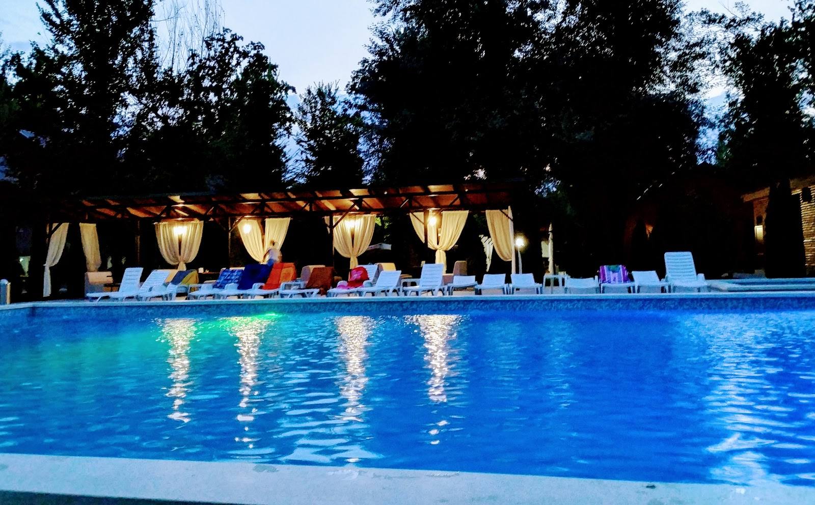 Poolside terrace at dusk with lounge seating and illuminated umbrellas