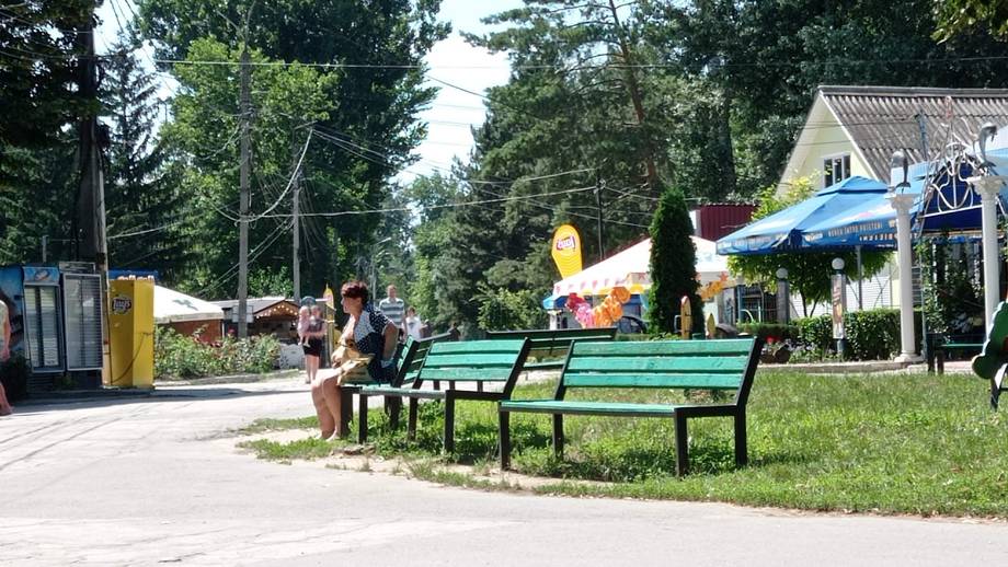 Outdoor terrace with green seating and tree-lined grounds, welcoming cafe or leisure venue