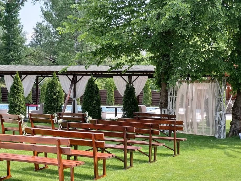 Outdoor terrace with wooden bench seating and pergola structure in garden setting