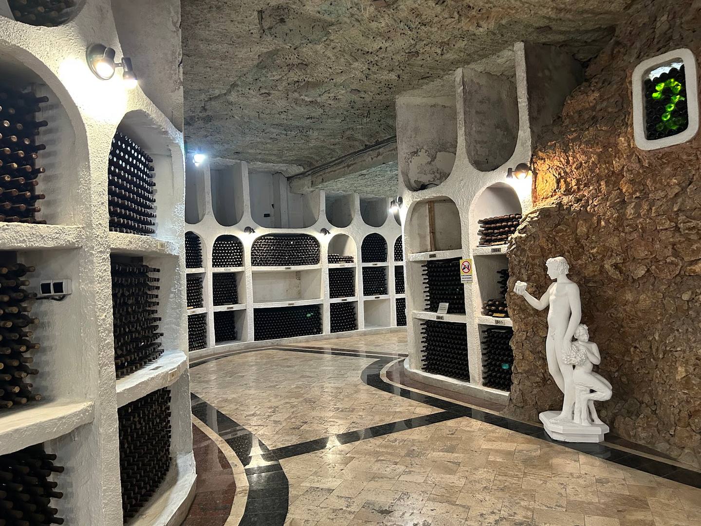 Wine cellar with barrel-shaped storage niches and classical sculpture