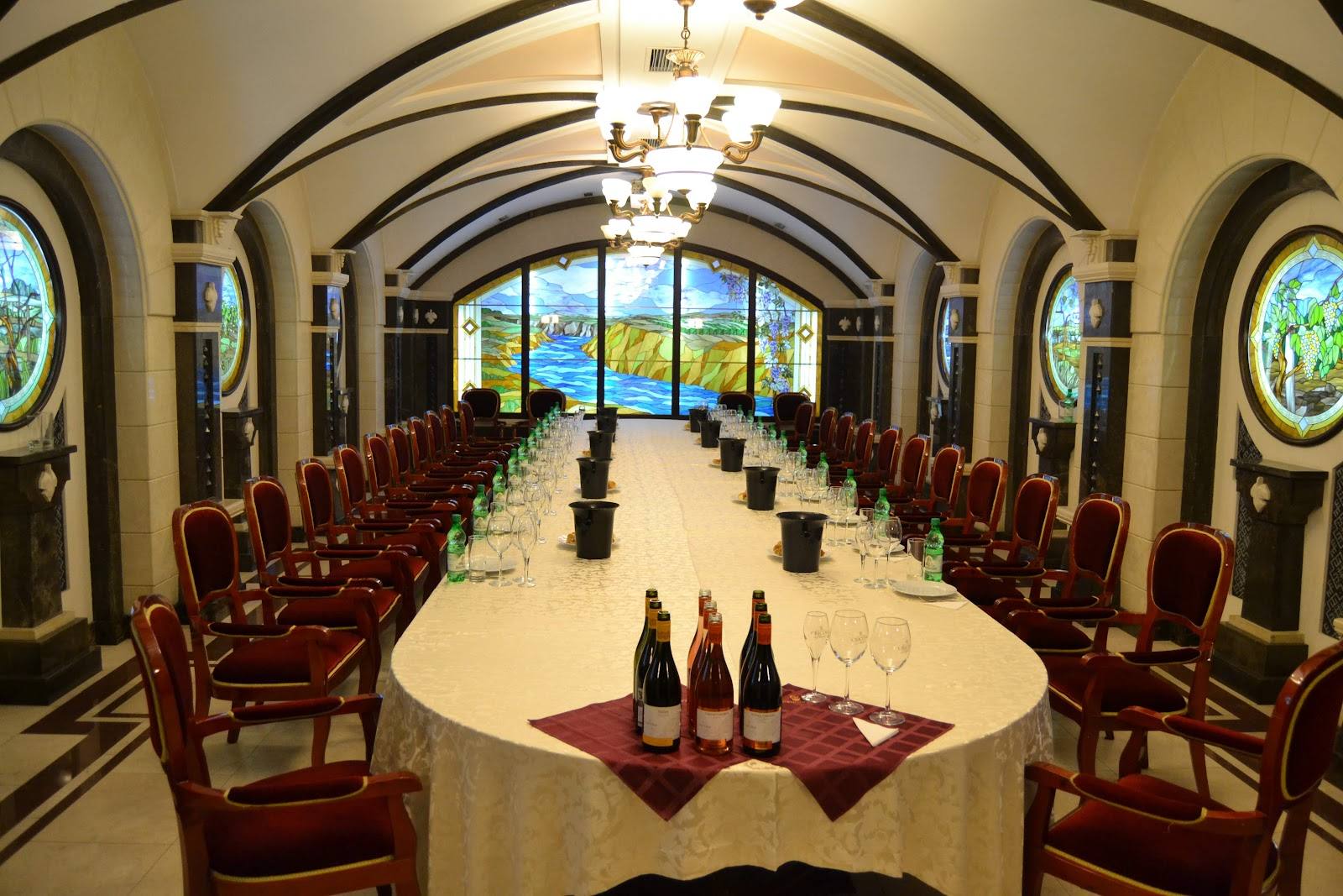 Elegant arched wine cellar interior with barrel-shaped seating rows and vineyard vista