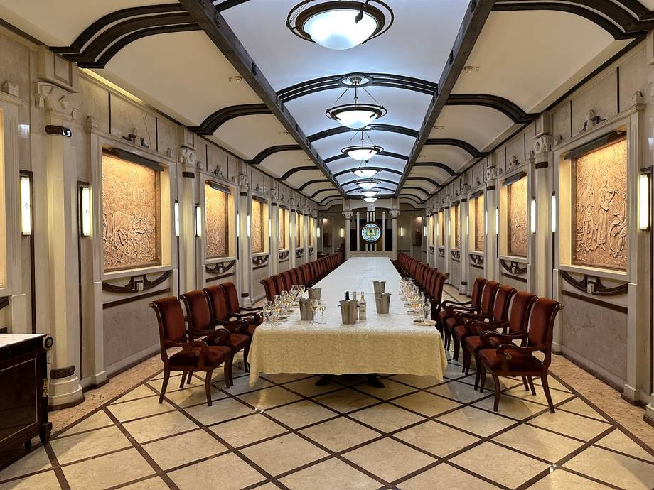 Art deco dining car with cream and burgundy interior, symmetrical seating, and geometric ceiling design