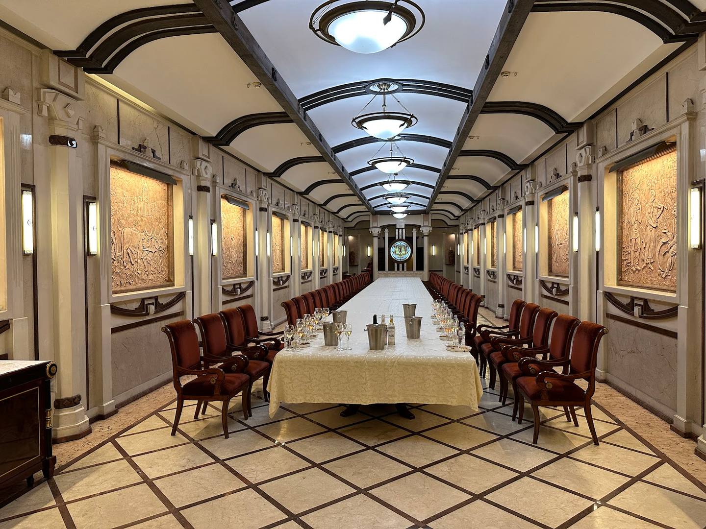 Art deco dining car with cream and burgundy interior, symmetrical seating, and geometric ceiling design