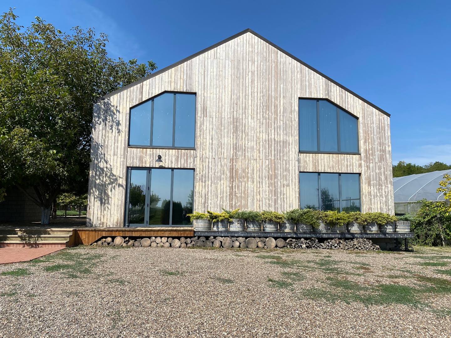 Modern light wood-clad rural building with large windows and terrace seating area
