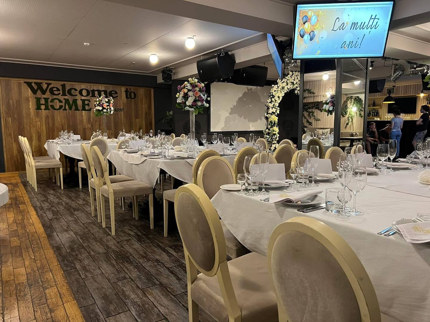 Modern event venue dining hall with elegant white-clothed tables and cream-colored chairs arranged for a reception