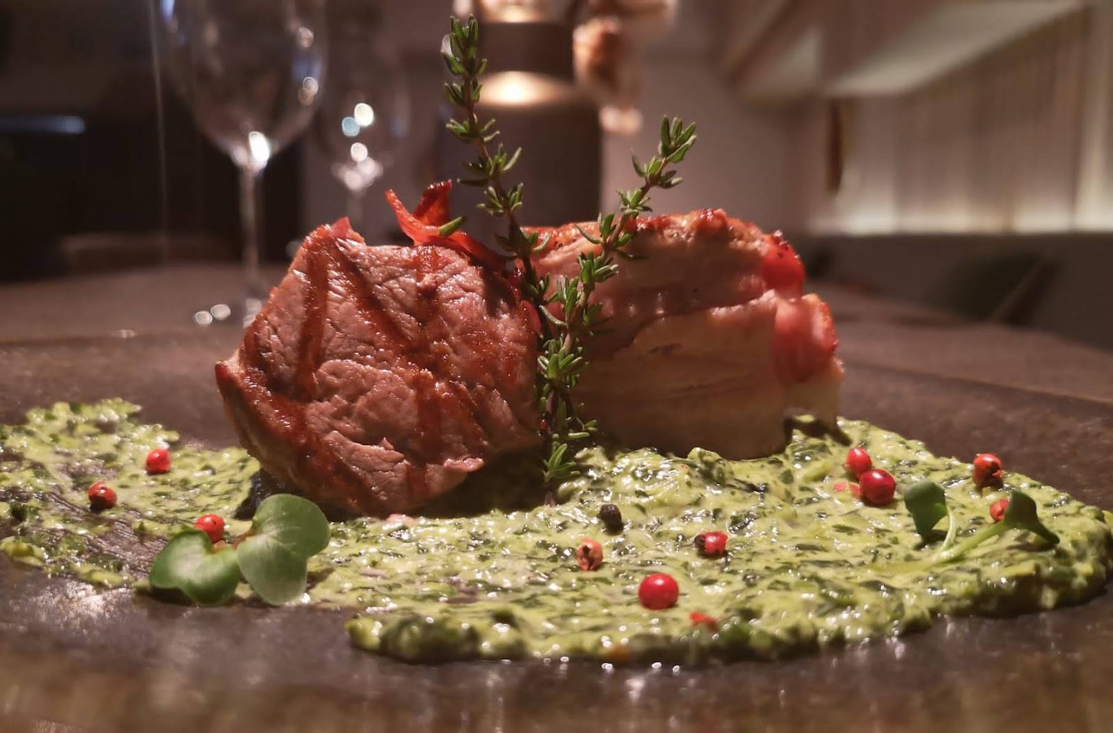 Plated steak with pistachio pesto and herb garnish