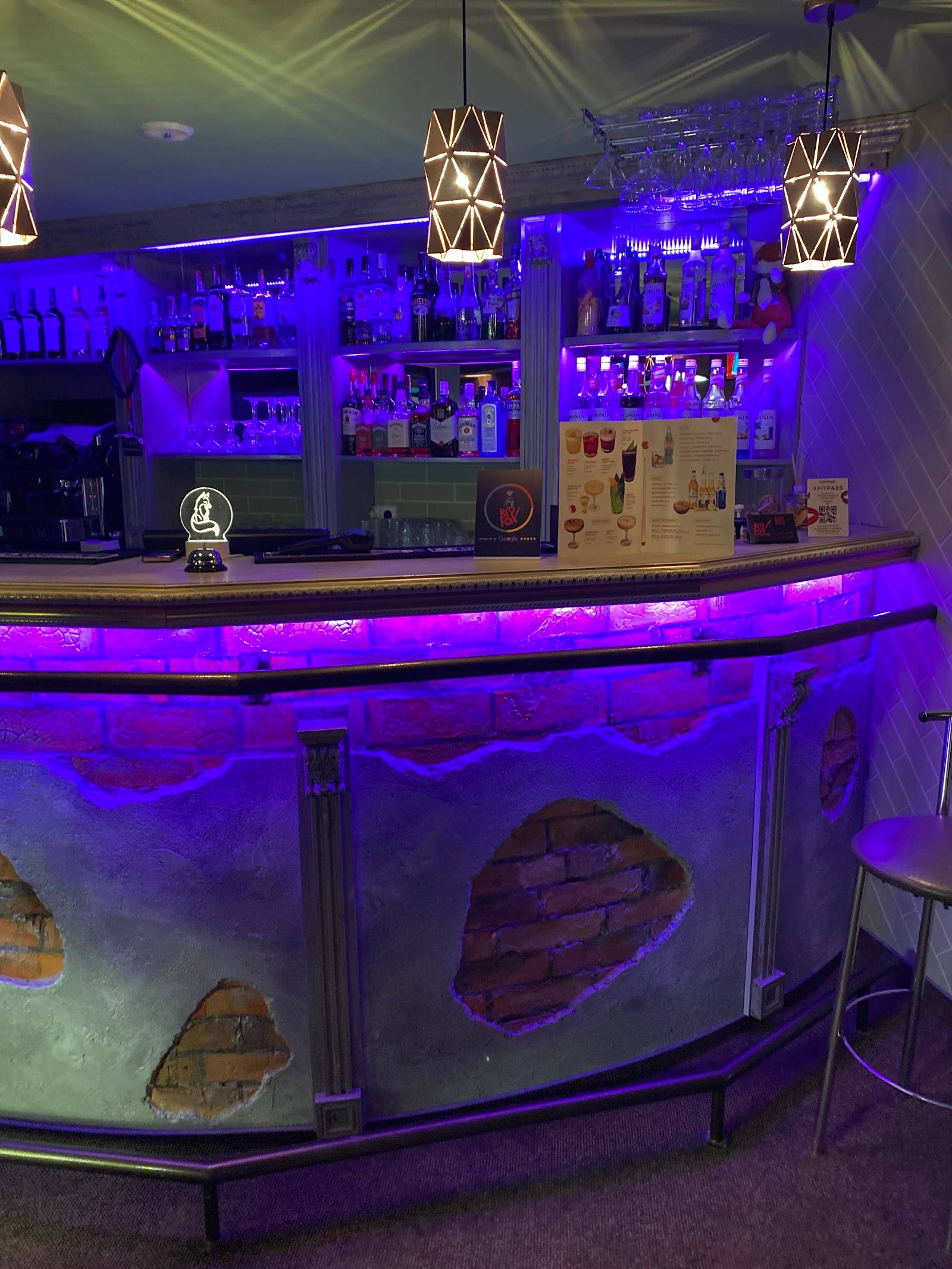 Modern bar counter with purple ambient lighting and geometric pendant fixtures, aquarium base detail visible