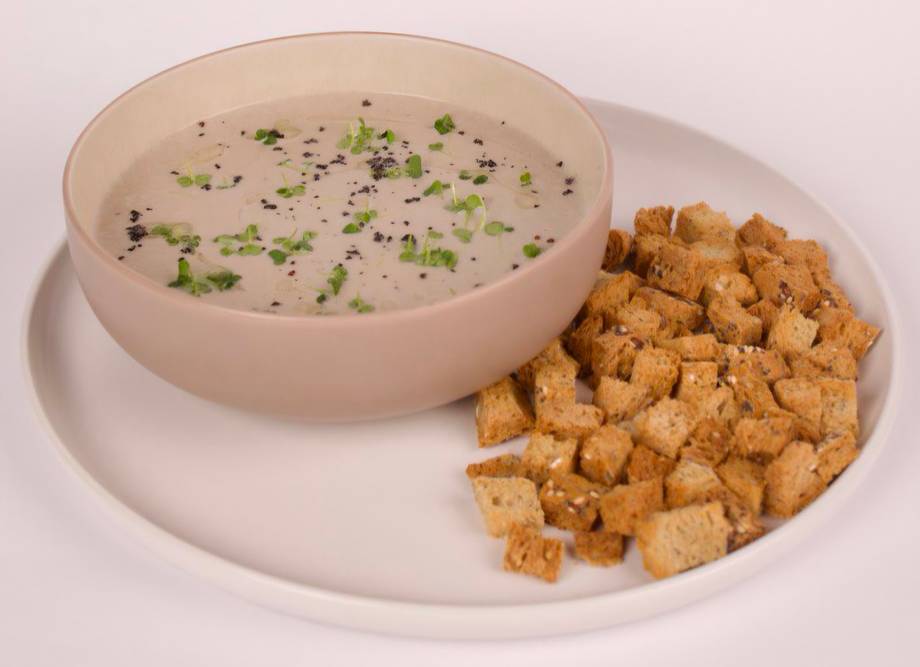 Creamy soup with croutons and fresh herbs garnish