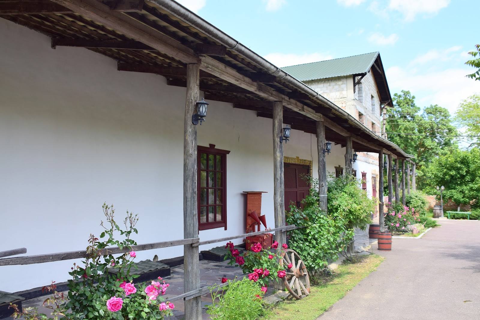Traditional white-walled building with covered terrace and flowering gardens along entrance
