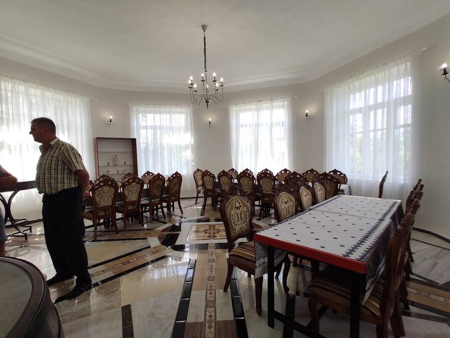Elegant banquet hall with high ceilings, chandeliers, and rows of upholstered dining chairs