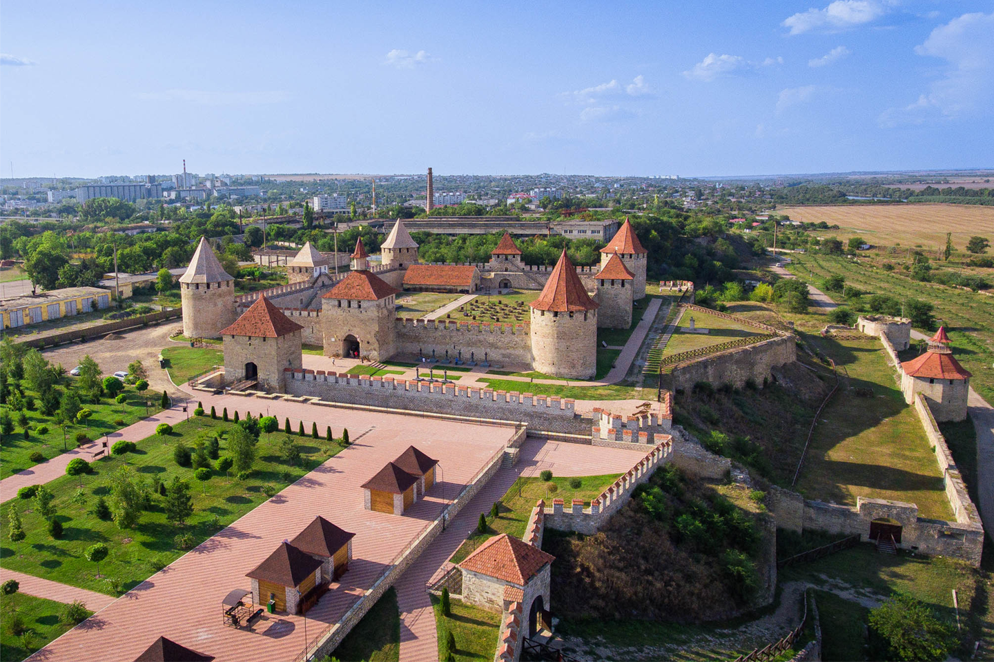 Medieval fortress with red-brick towers and manicured grounds surrounded by Moldovan countryside