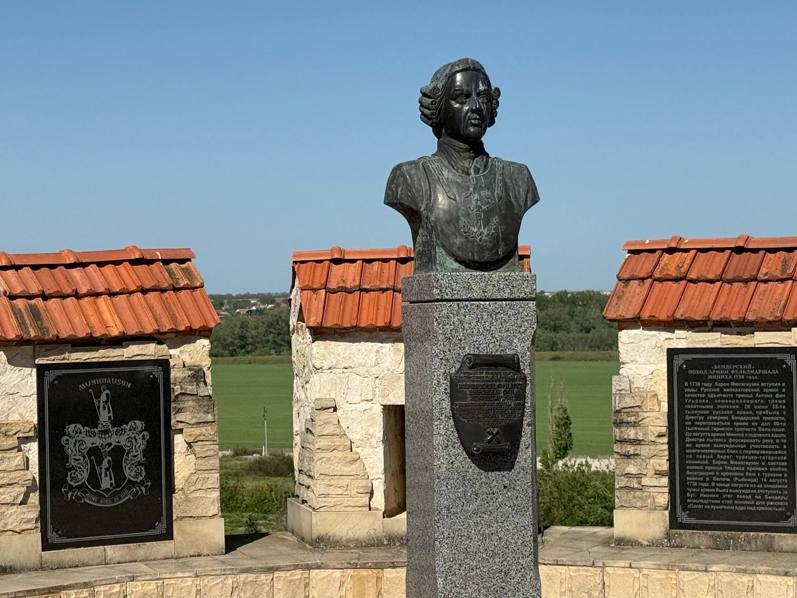 Bronze bust monument with memorial plaques overlooking open countryside