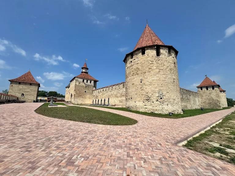 Historic fortress with distinctive round tower and red-tiled roofs under clear blue sky