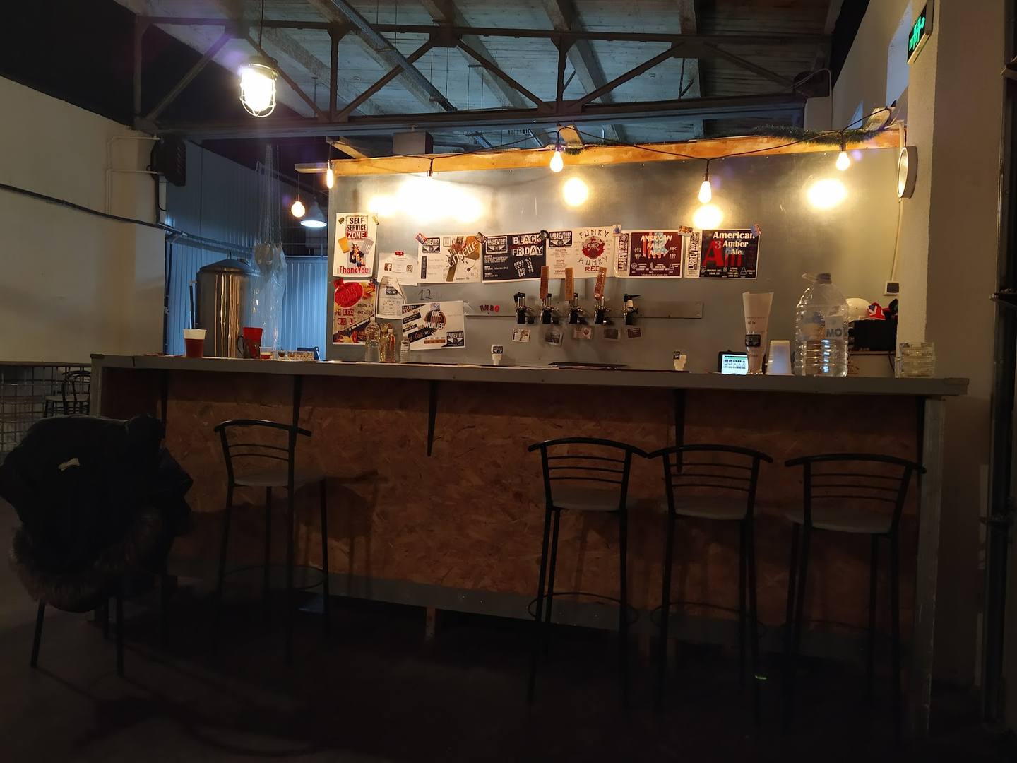 Bar counter with seating, warm overhead lighting, and espresso machine setup