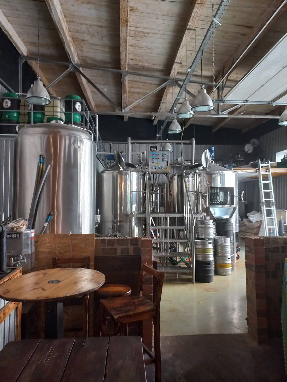 Craft brewery cellar with large fermentation tanks and wooden seating area