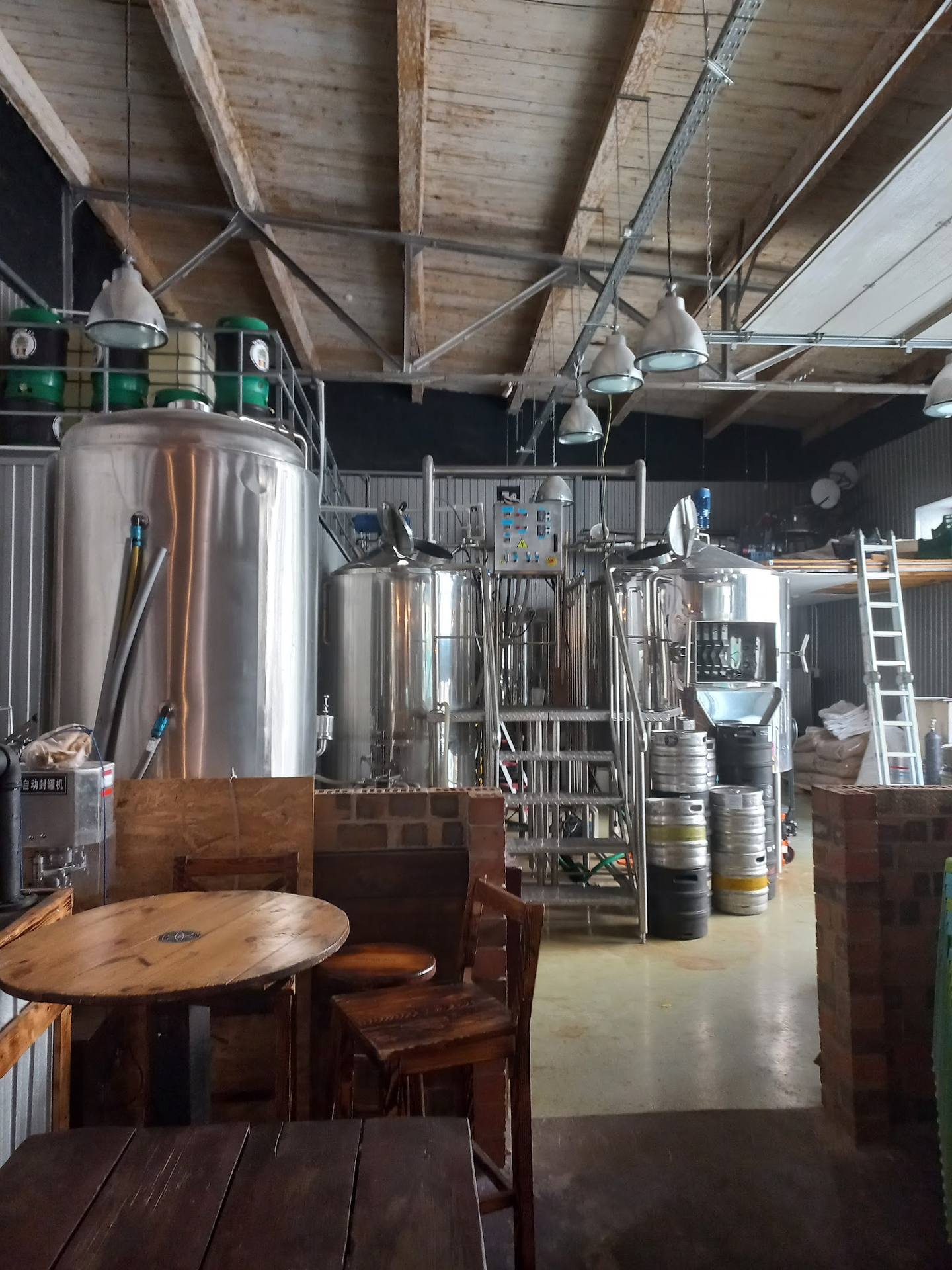 Craft brewery cellar with large fermentation tanks and wooden seating area
