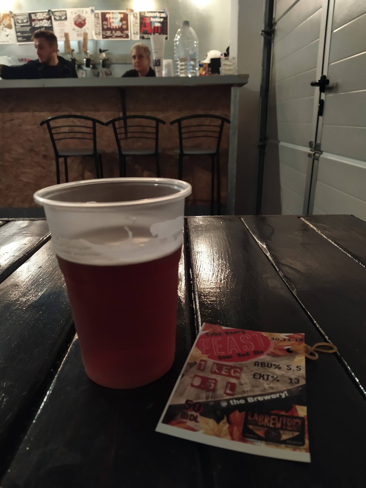 Craft beer pint with brewery merchandise on bar table
