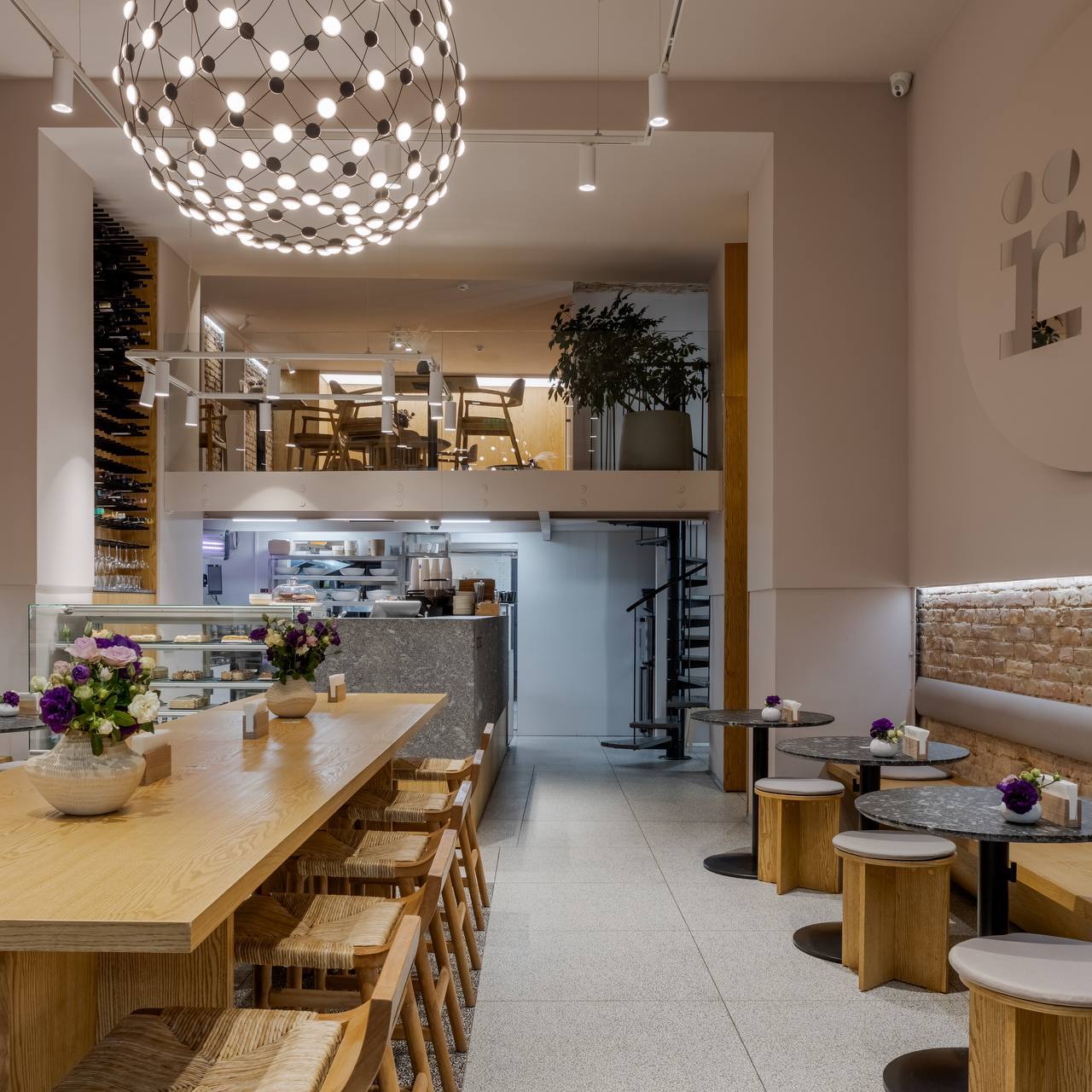 Modern cafe interior with open kitchen, wooden counter seating, and contemporary lighting