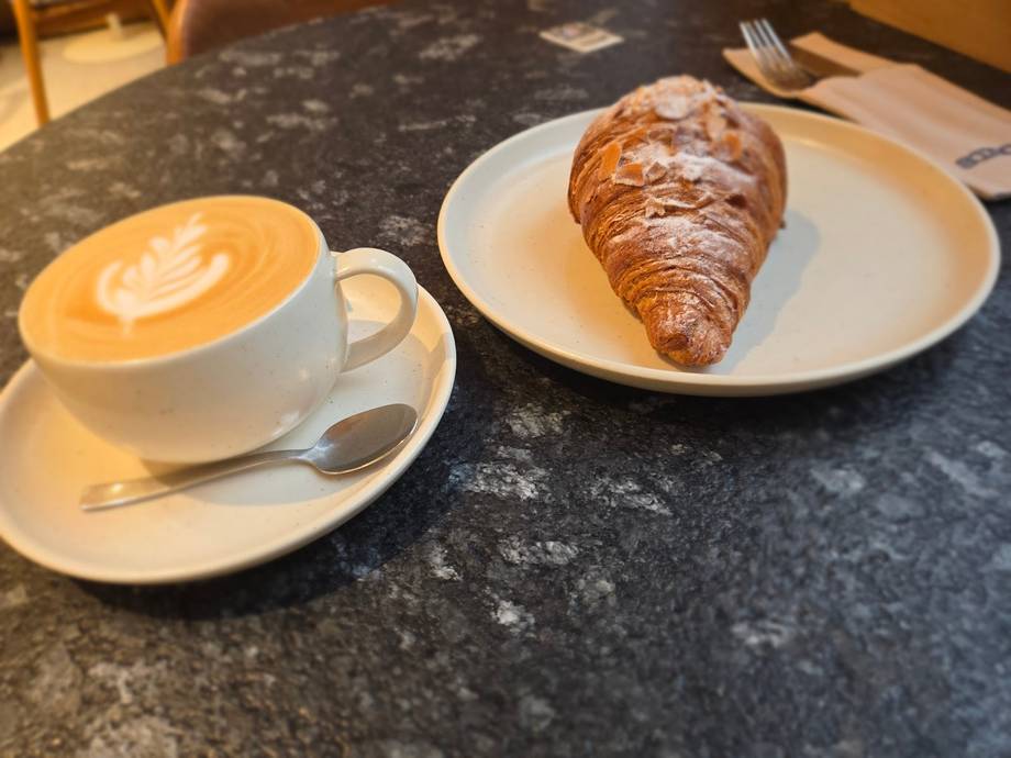 Cappuccino with latte art and fresh croissant on dark stone table
