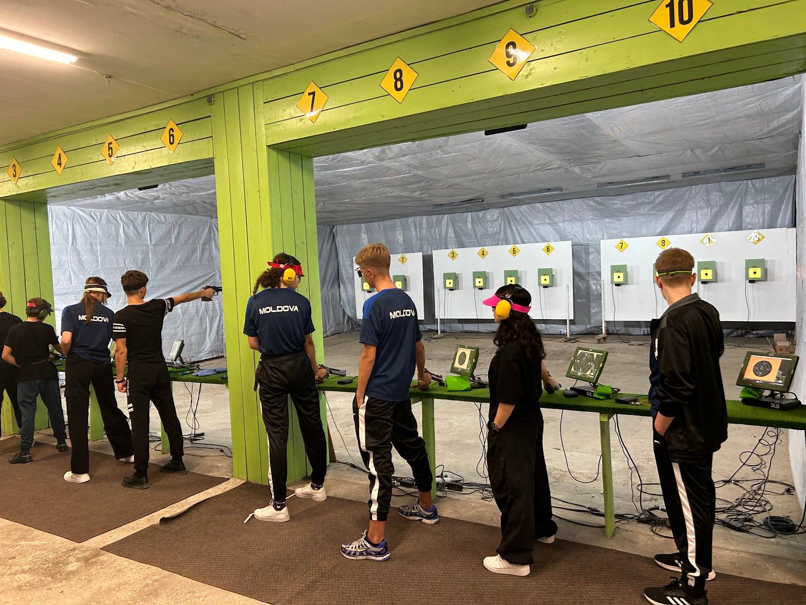Group of participants at an indoor shooting range with numbered target stations